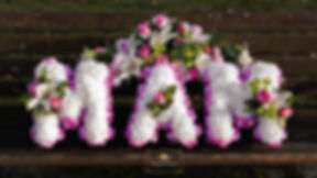 A silk flower tribute spelling the word Mam in white and pink silk blooms